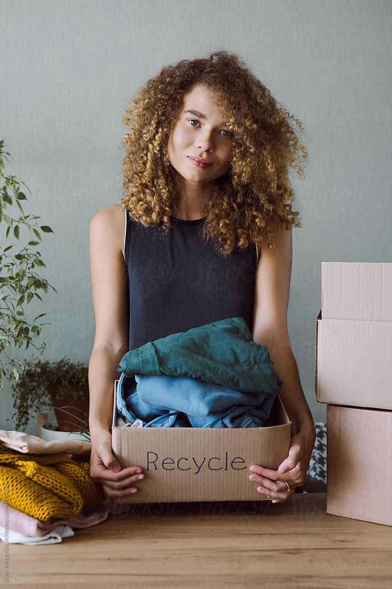 Curly young woman collects old things for recycling