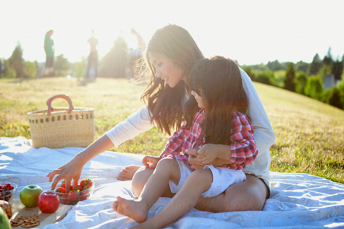 Mother and daughter grabbing fruit at summer picnic