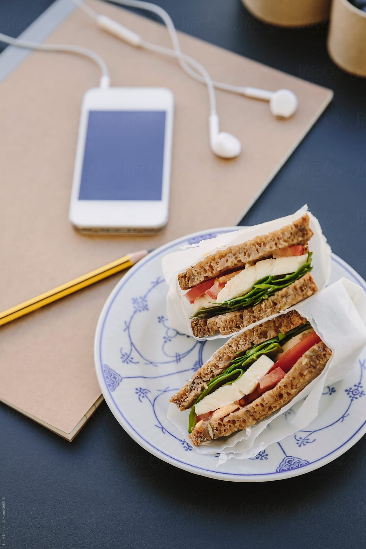 Vegetarian rye bread sandwich on vintage plate next to smart phone
