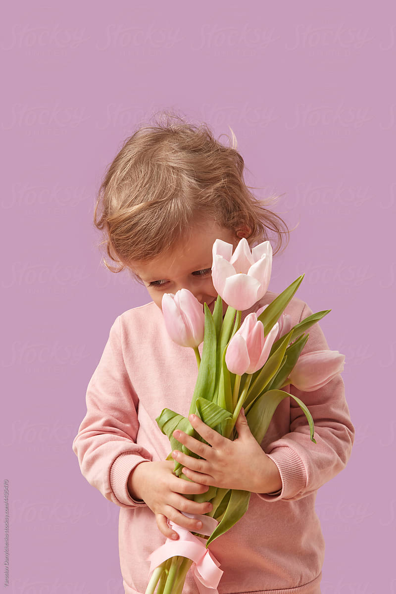 Little female kid posing in studio with bouquet of tulips