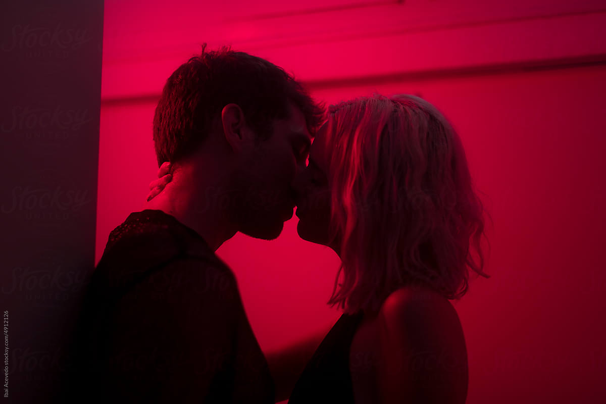 Lovers silhouettes kissing with red neon light