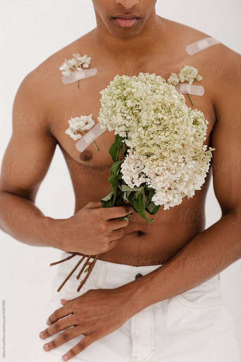 Shirtless black man standing with bouquet