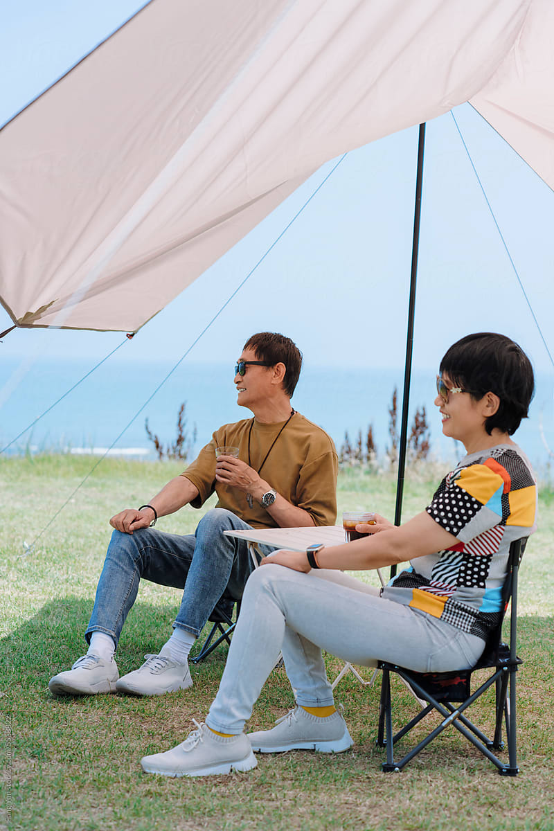 mature couple enjoying a camping trip on a grassy hill overlooking sea
