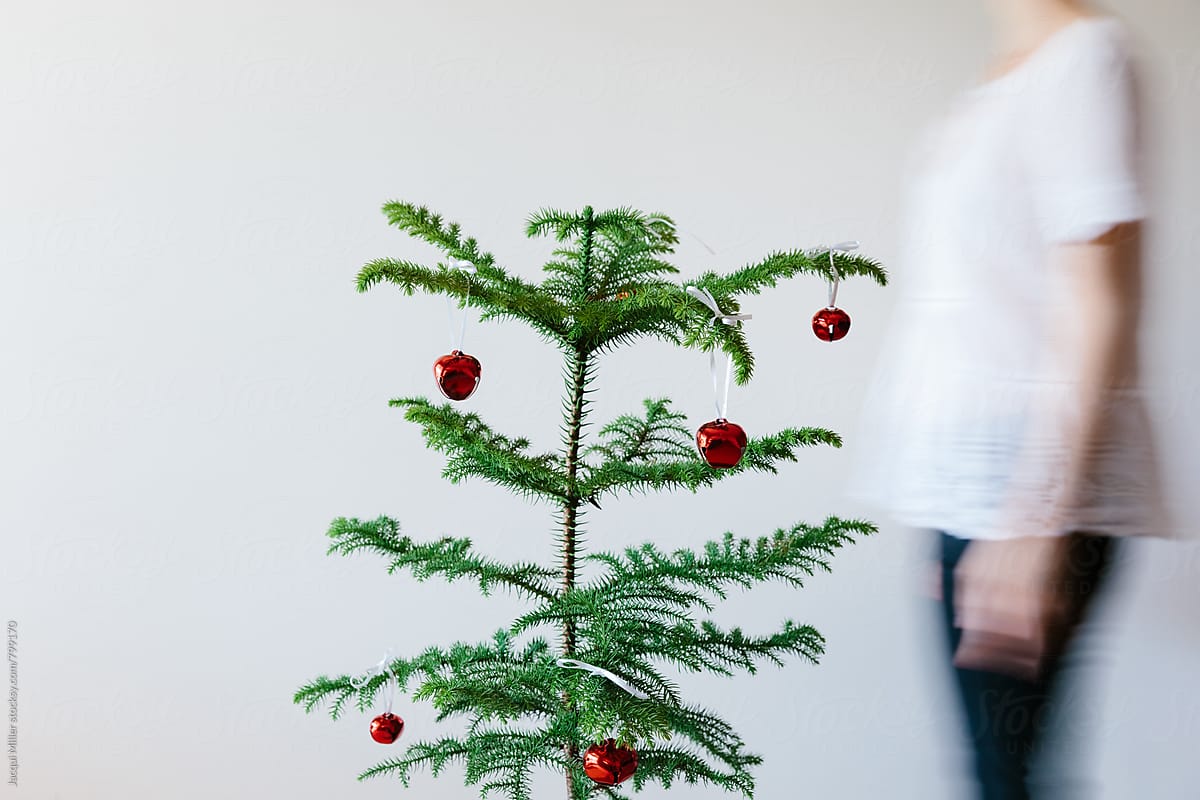 Unrecognisable female walking past small Christmas Tree