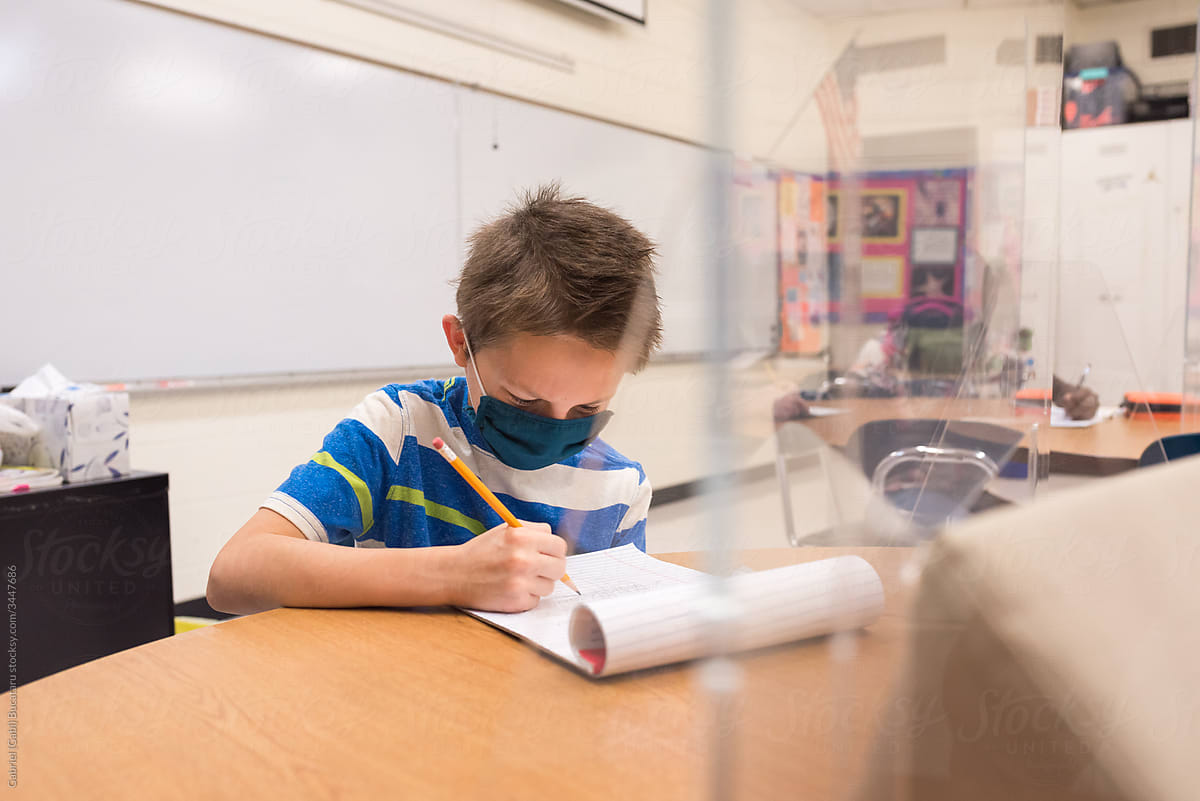 Boy with mask working in the classroom