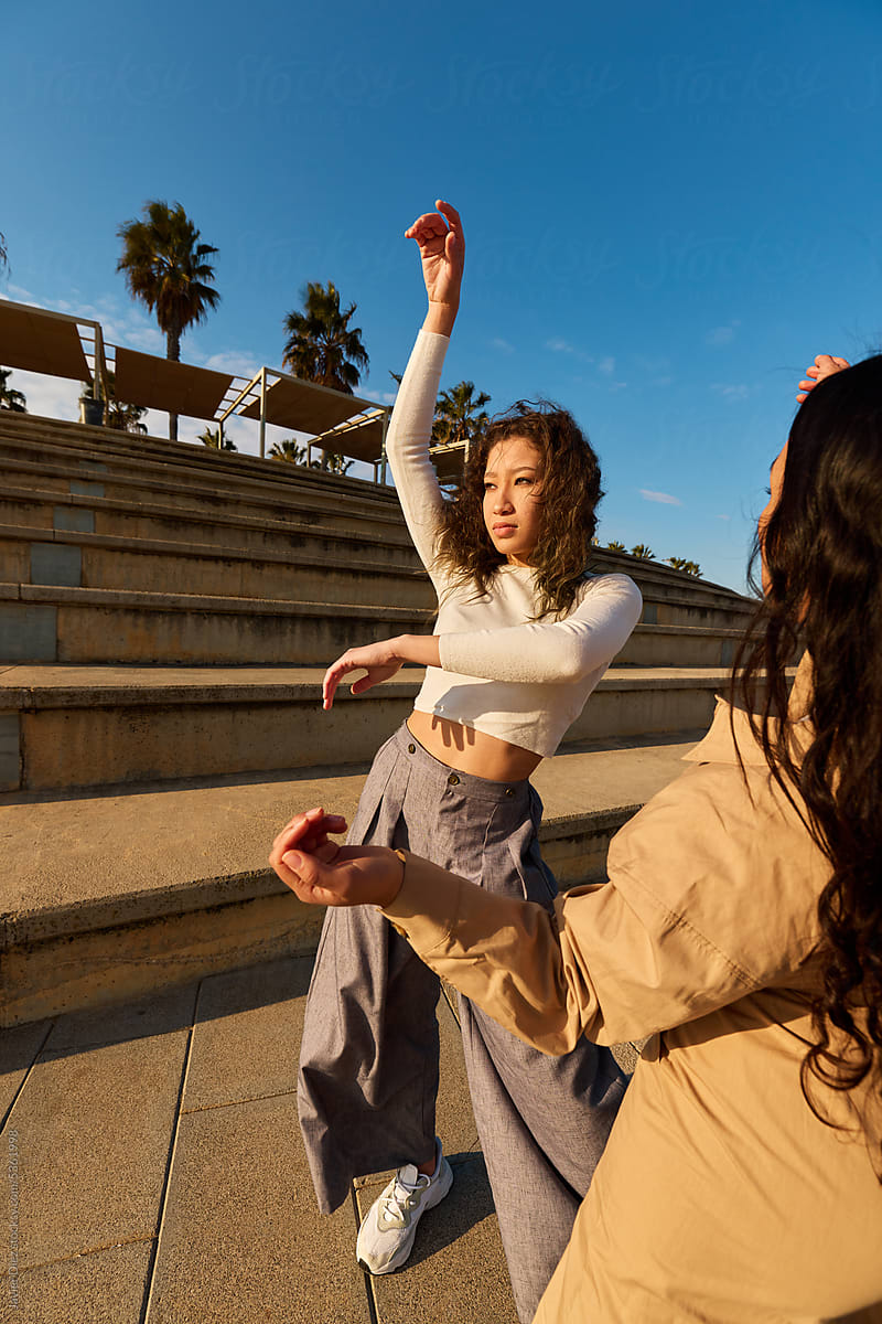 Trendy Young Women Dancing In Park In Sunlight by Stocksy