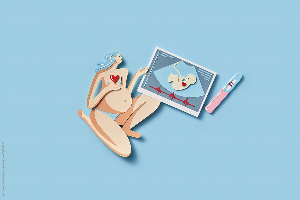 Papercraft figure of pregnant woman holding sonogram of her baby
