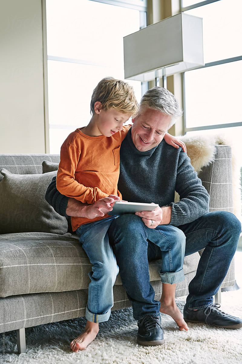 Father and son looking at digital tablet on sofa