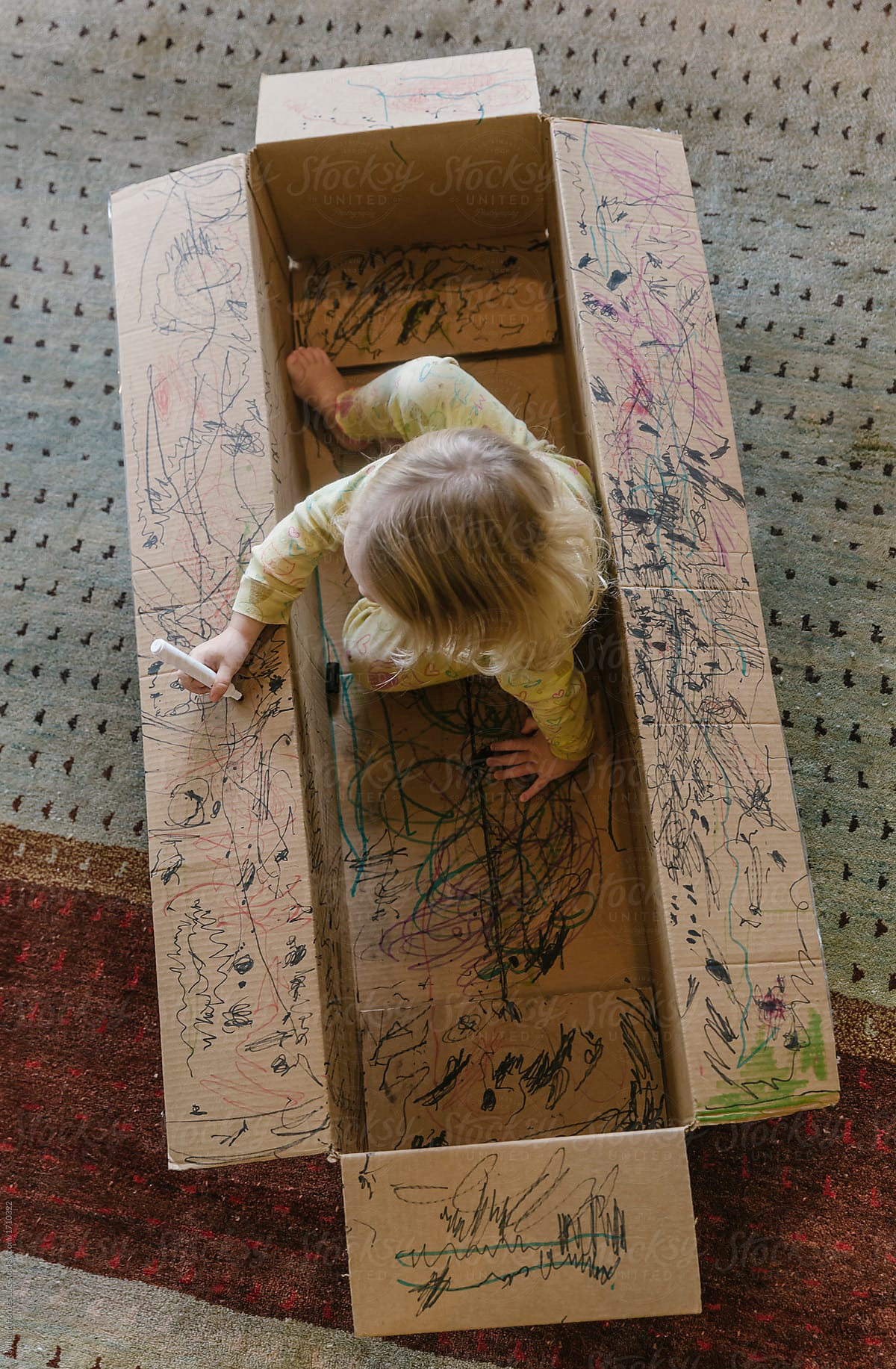 Child Drawing while Playing in Cardboard Box