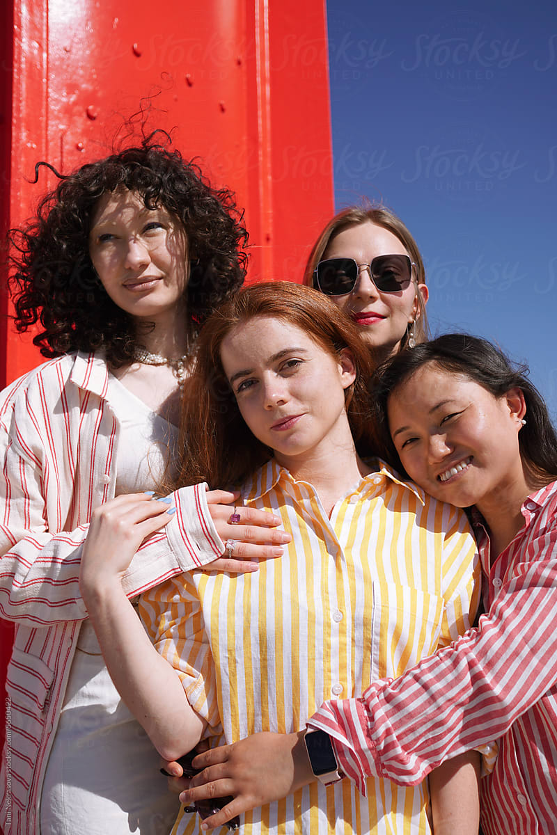 Four young female friends traveling together, red background