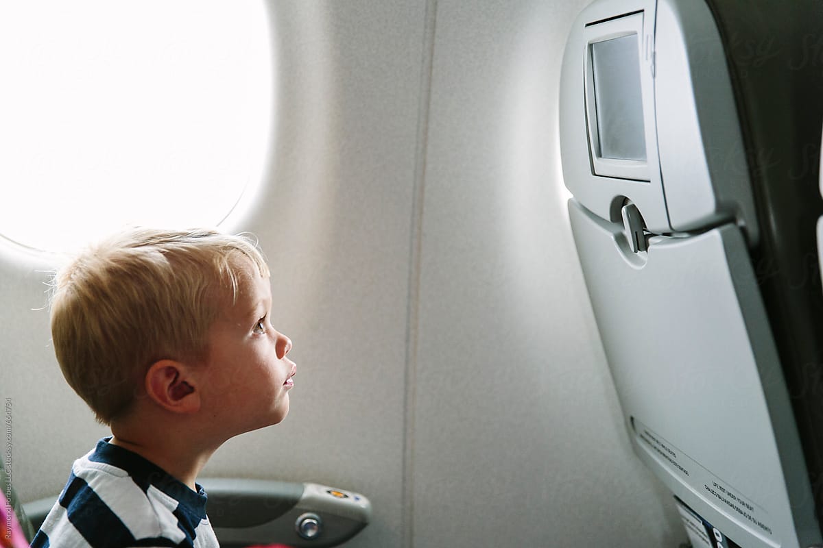 Portrait of young boy sitting in plane seat watching video on screen