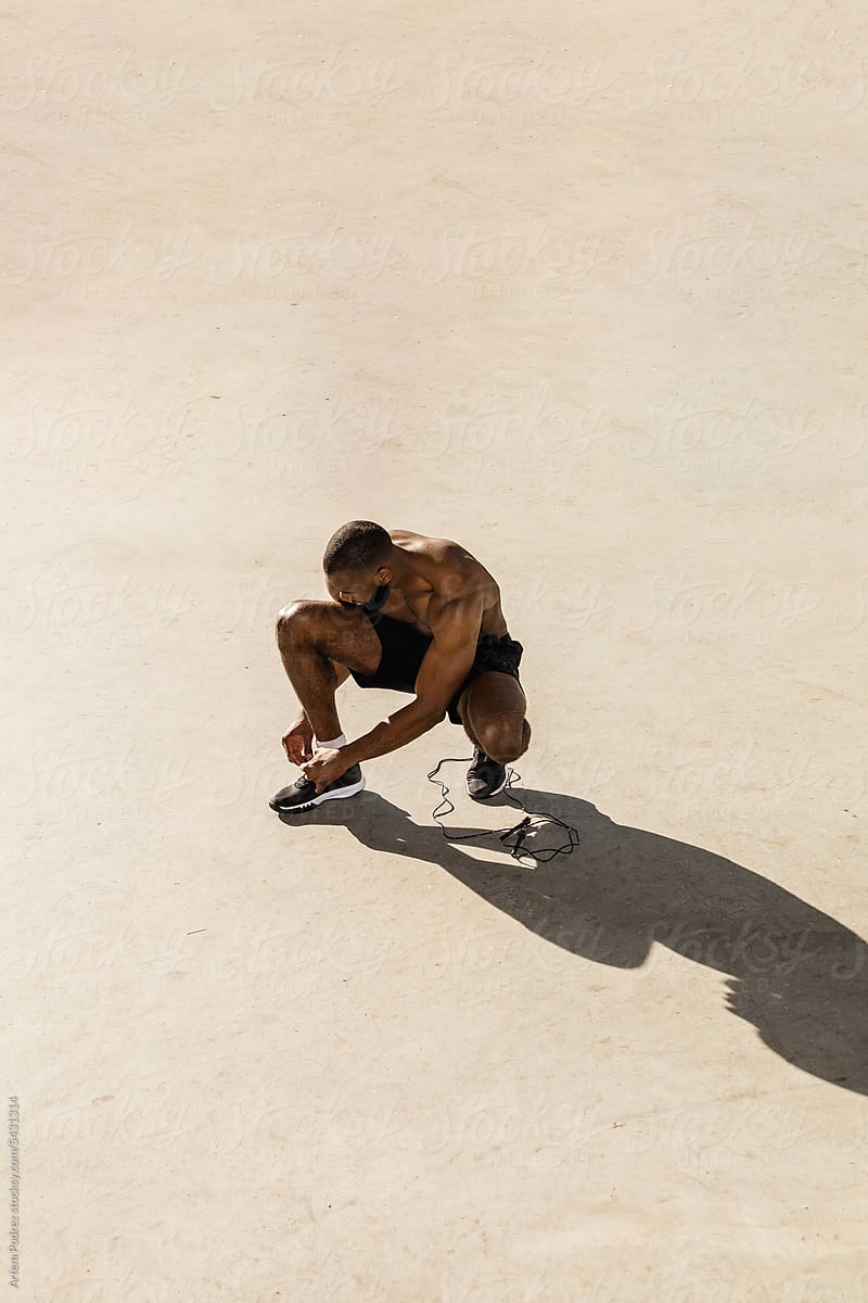 an athlete ties his shoelaces during a workout outside