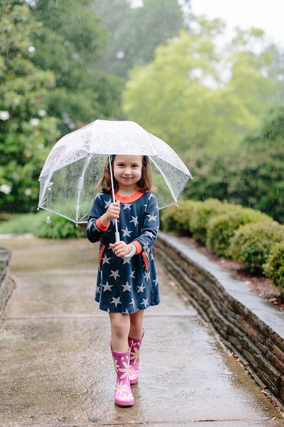 Cute young girl walking in the rain with an umbrella