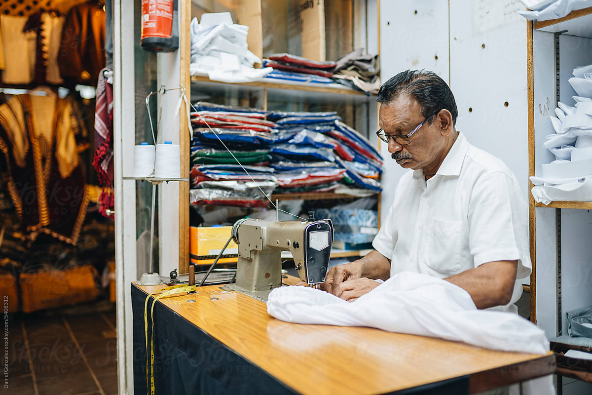 Calm Indian tailor creating shirt in workshop