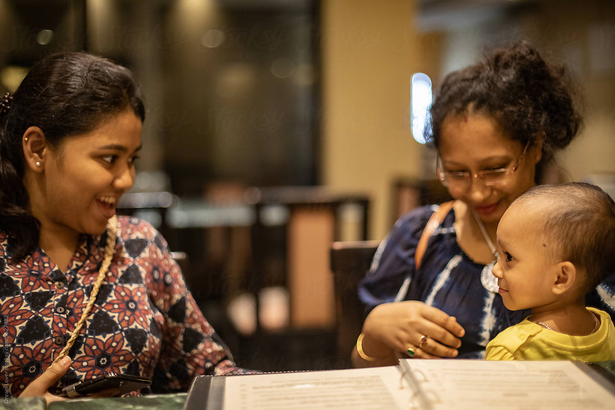 Happy Indian family making interaction inside a restaurant