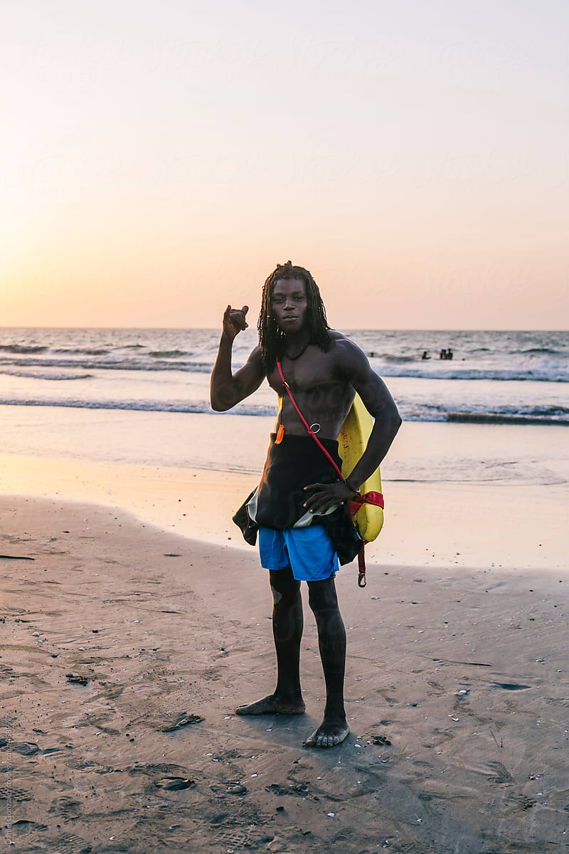 Black rescuer showing shaka gesture on seashore