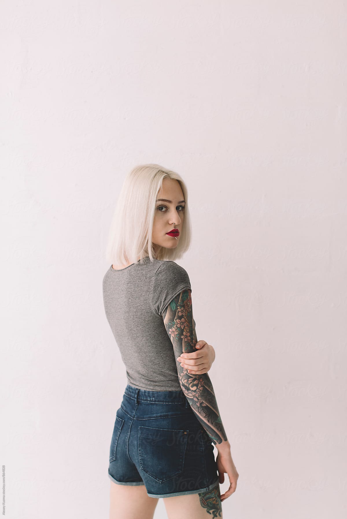 portrait of young blond woman with tattoos on the white background