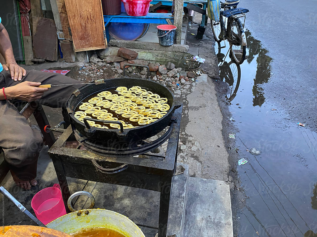 A man is frying  Jilaibi,a popular sweet in a roadside shop