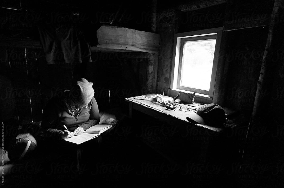 Woman writing in journal inside a hut, New Zealand.