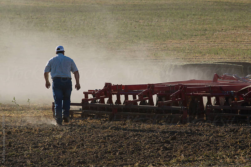 farmer walks behind plow inspecting ground
