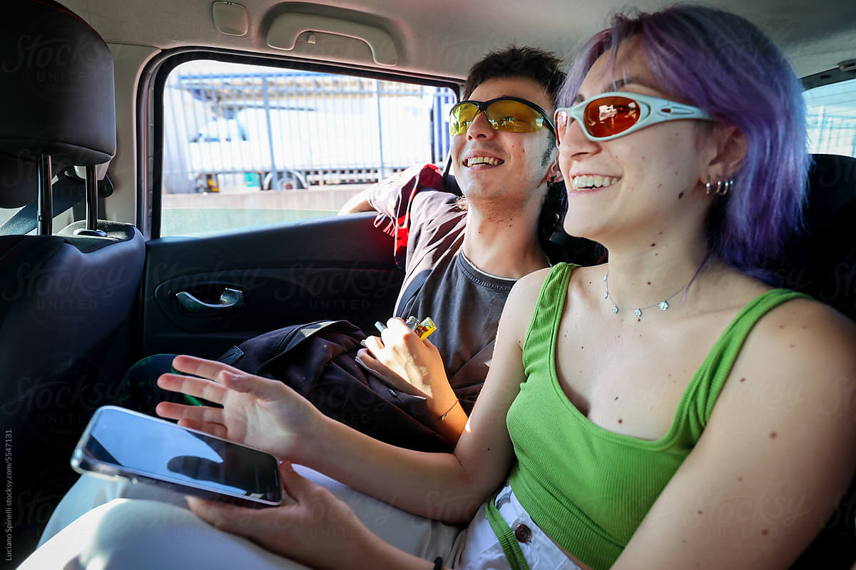 Cool fashionable Zoomers using phone and having fun inside car