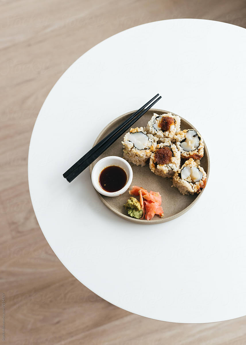 Spicy scallop sushi in ceramic plate on white table with chopsticks