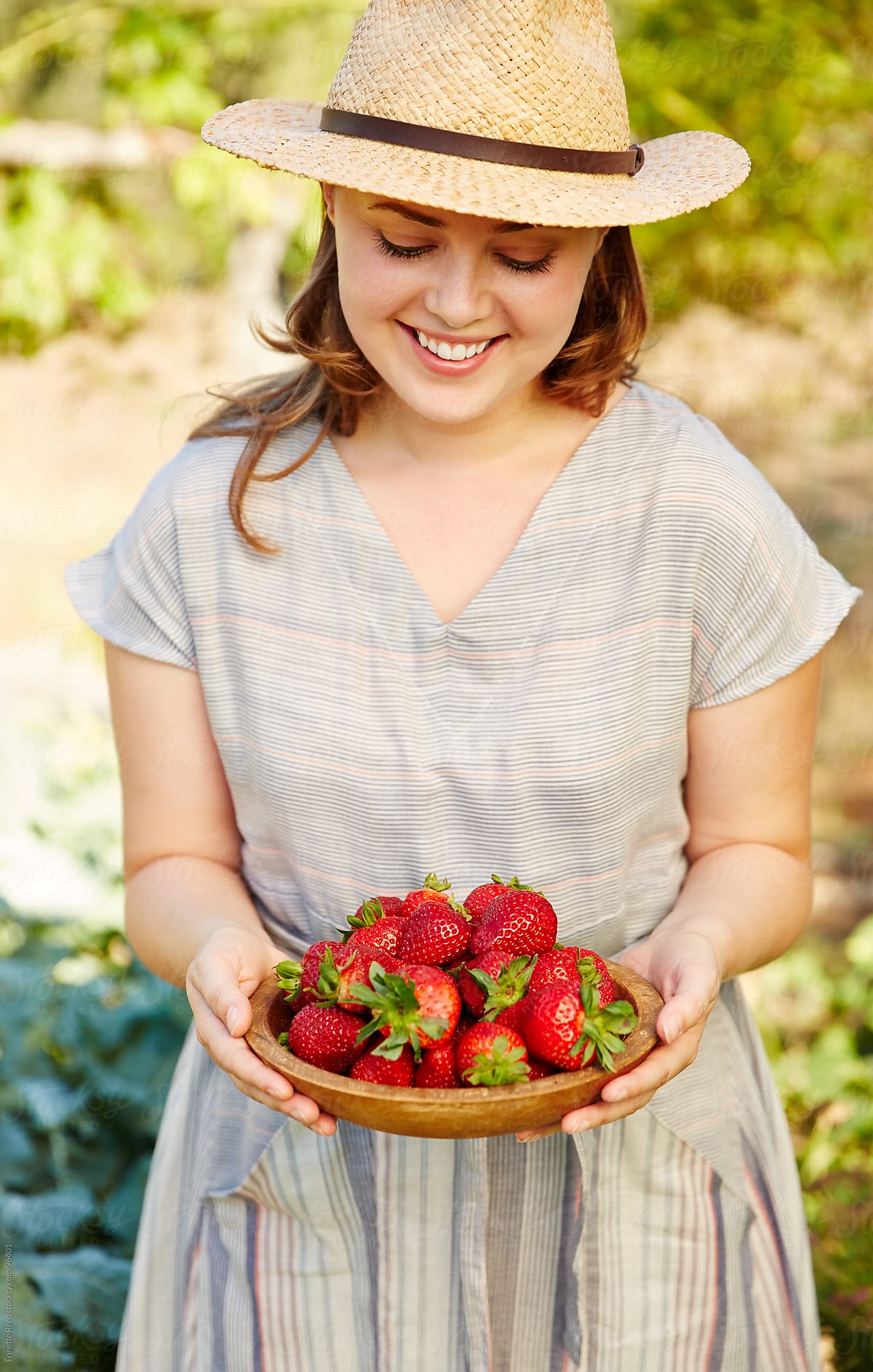 Woman farmer holding fresh picked strawberries on organic farm