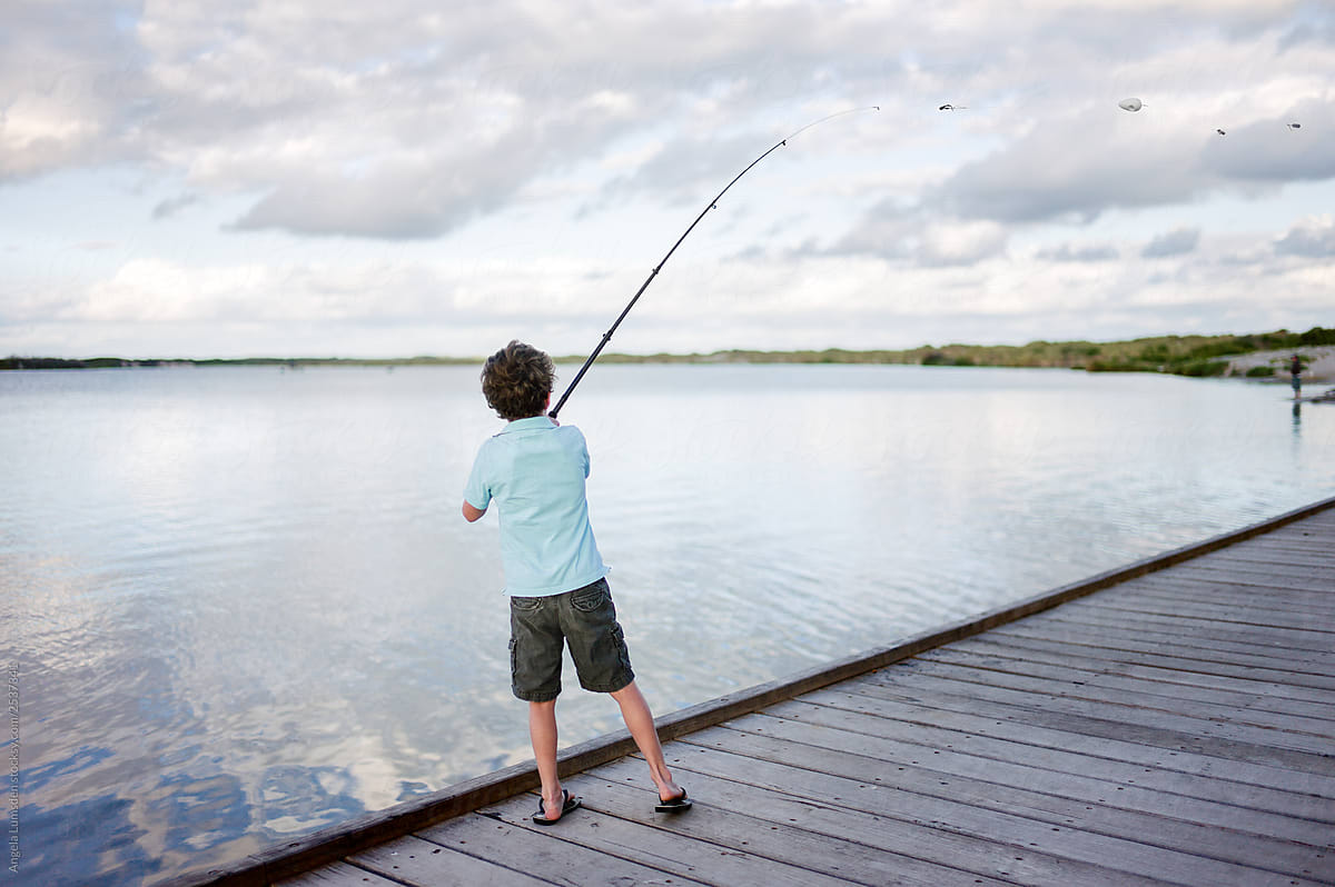 Child Casting A Line From A Fishing Rod Off A Dock At A River Mo by  Stocksy Contributor Angela Lumsden - Stocksy