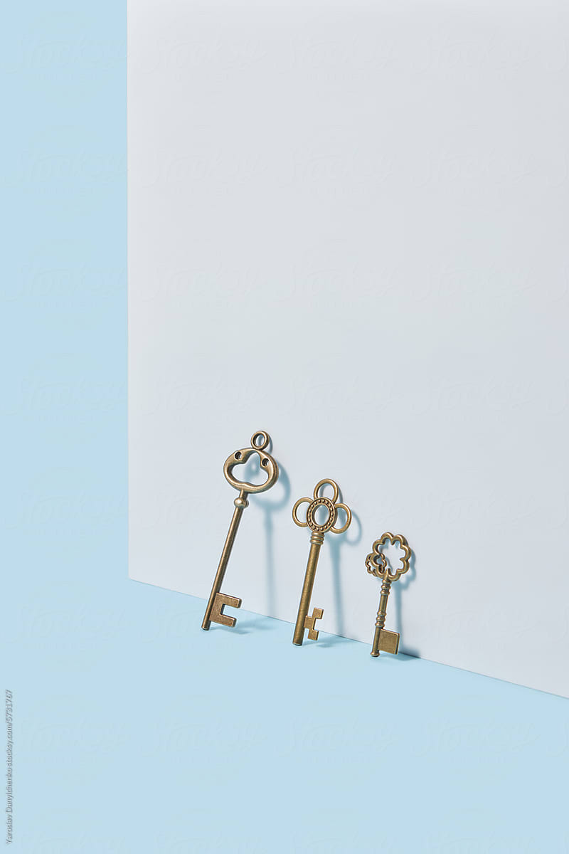 Three vintage ornate keys leaning on decorative white wall