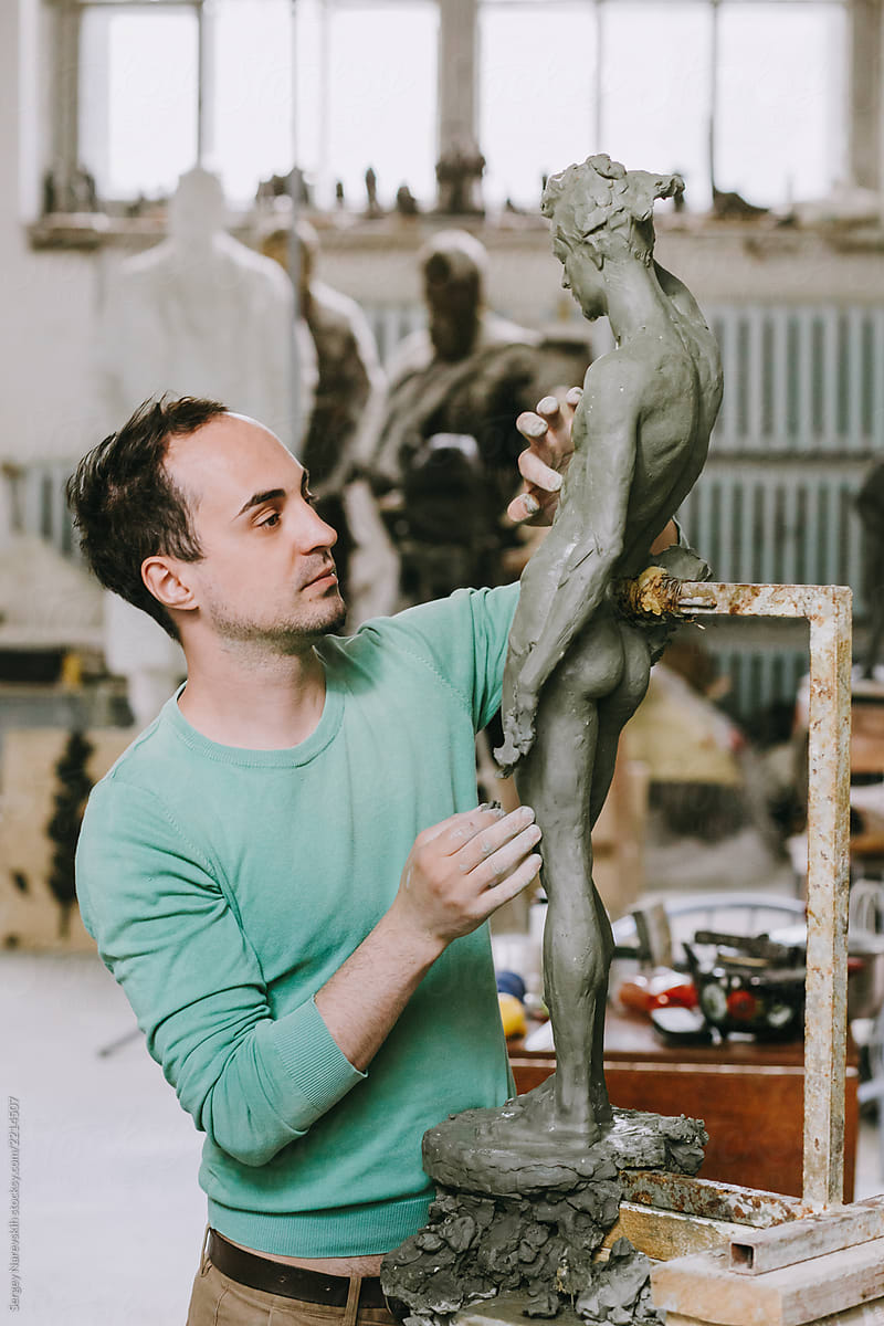 Inspired man working on sculpture in studio
