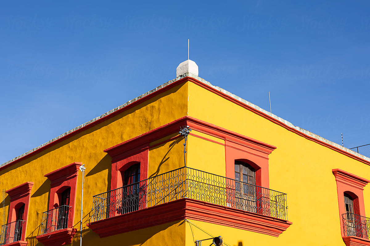 The corner of a yellow building with orange views and balcony