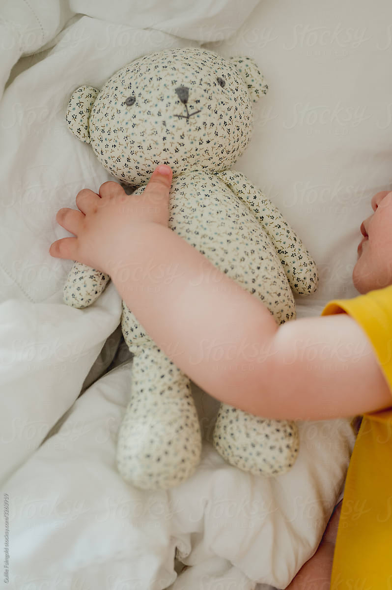 Crop baby hugging toy on bed