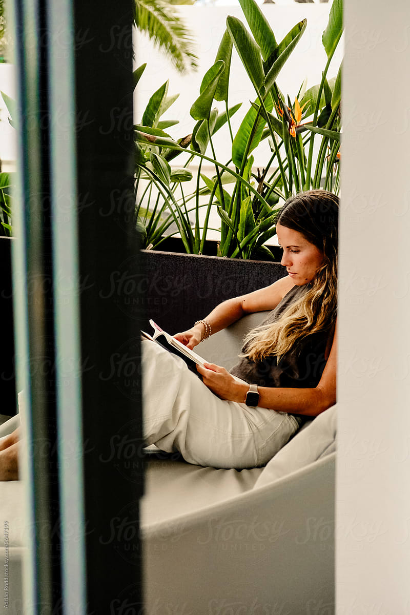 Relaxed Reading: 25-35-Year-Old Woman Amidst Lush Greenery at a Hotel