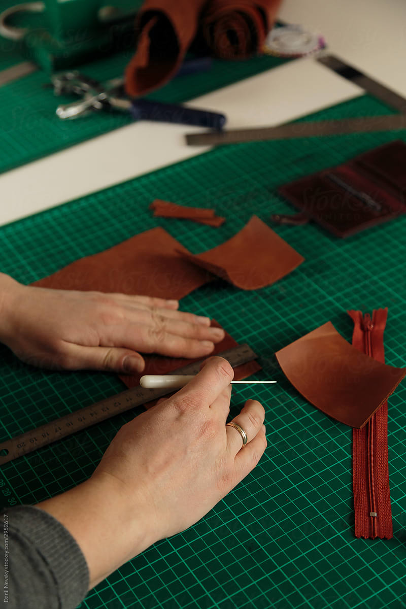 Anonymous female tailor creating leather accessory in workshop