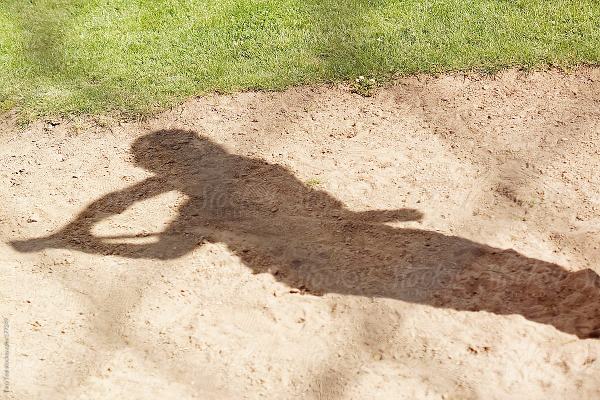 The shadow of a baseball player swinging a bat