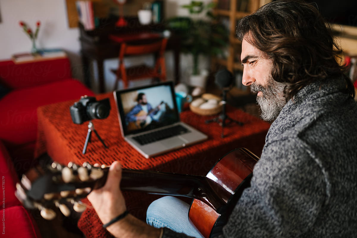 Mature man playing guitar during online lesson