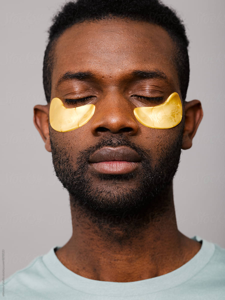 Relaxed man using gold under eye mask