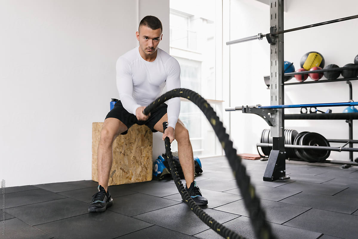 Man workout at the gym using a rope