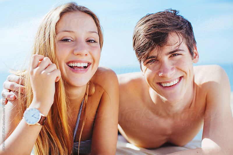 Portrait of a teenage couple having fun tanning on the beach in summer.