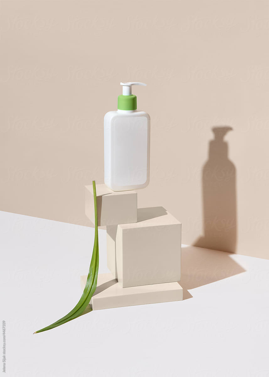 Natural facecare product in a white bottle and green leaf on its left.