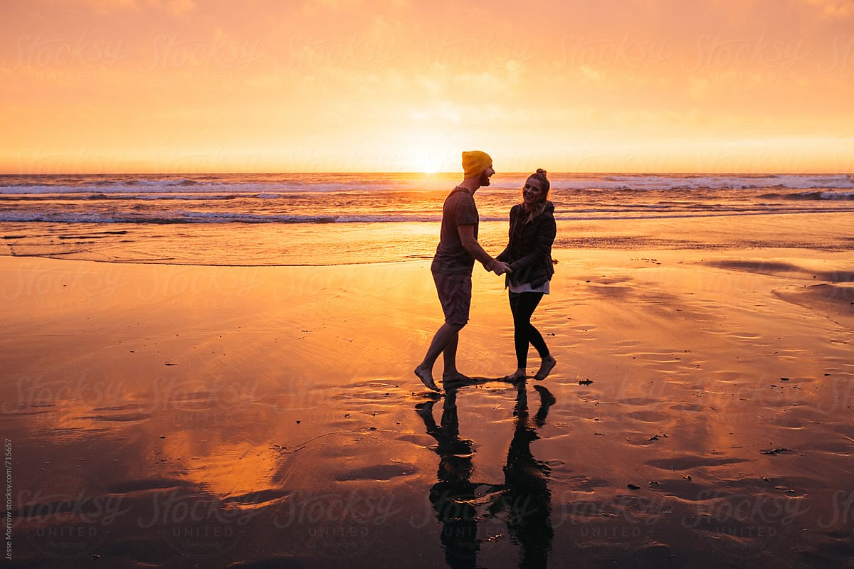 couple in love on the beach kissing and holding hands during sunset
