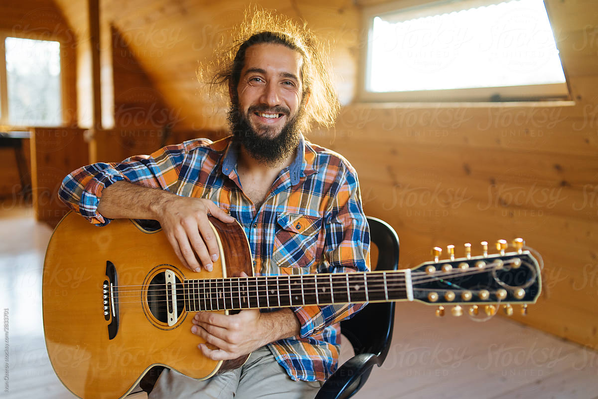 Portrait of a smiling bearded man with a guitar