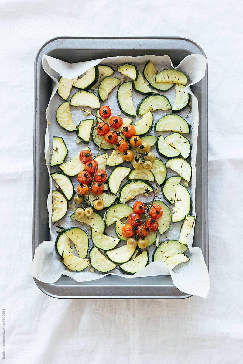Roasted tomatoes on the vine with zucchini on baking tray