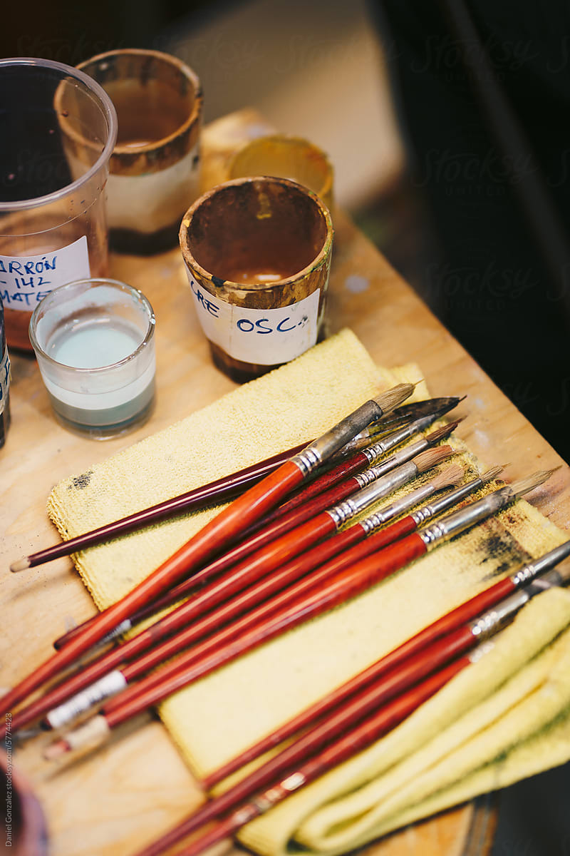 Various paintbrushes and glass jar with paint on wooden