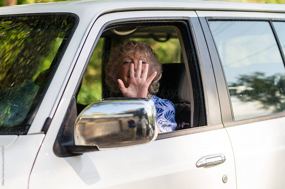 happy senior woman waving from car