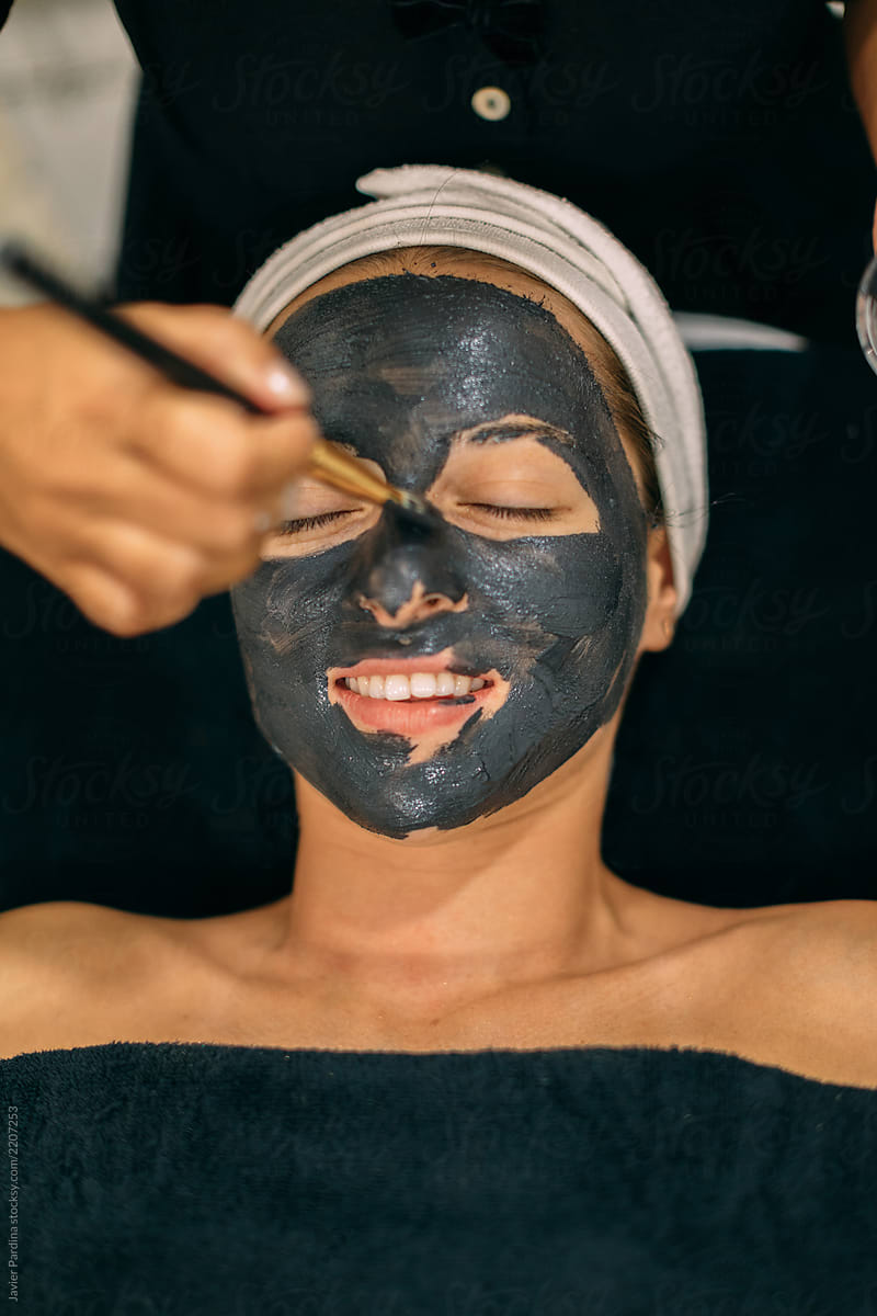 Woman applying dark mask at spa center