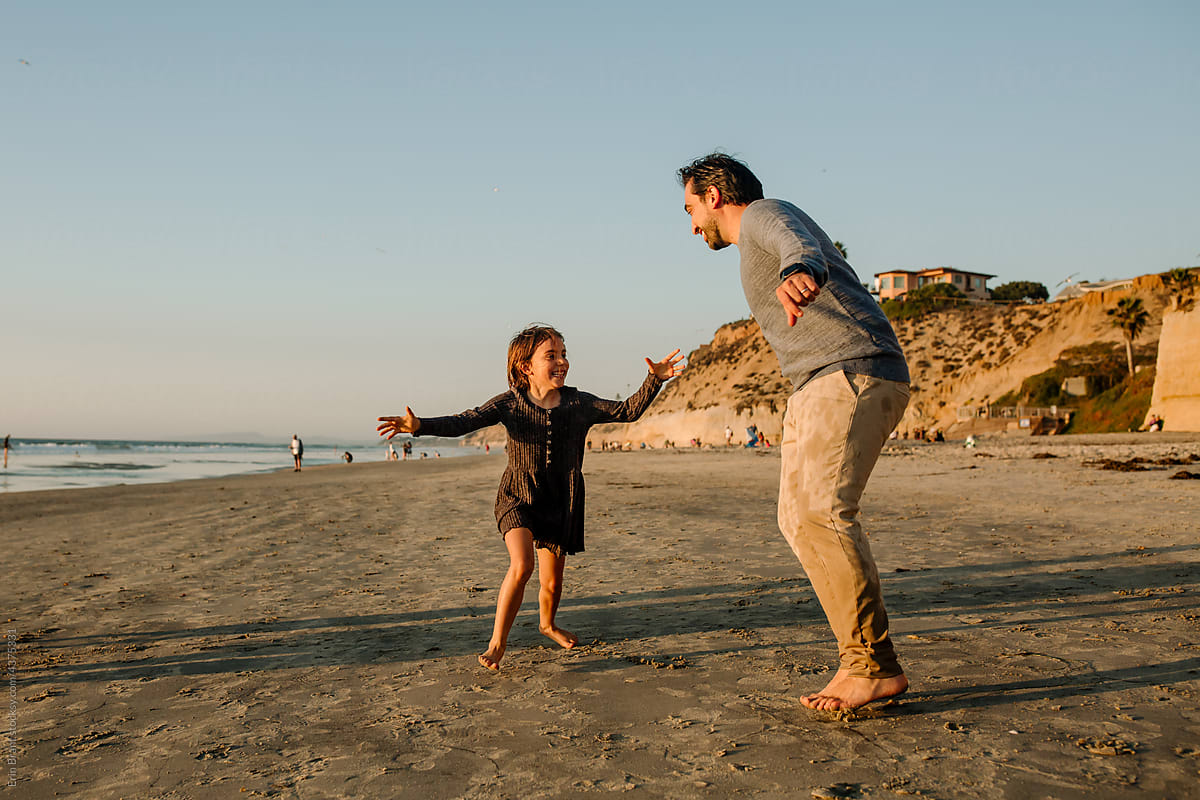 Dad and daughter dancing on beach