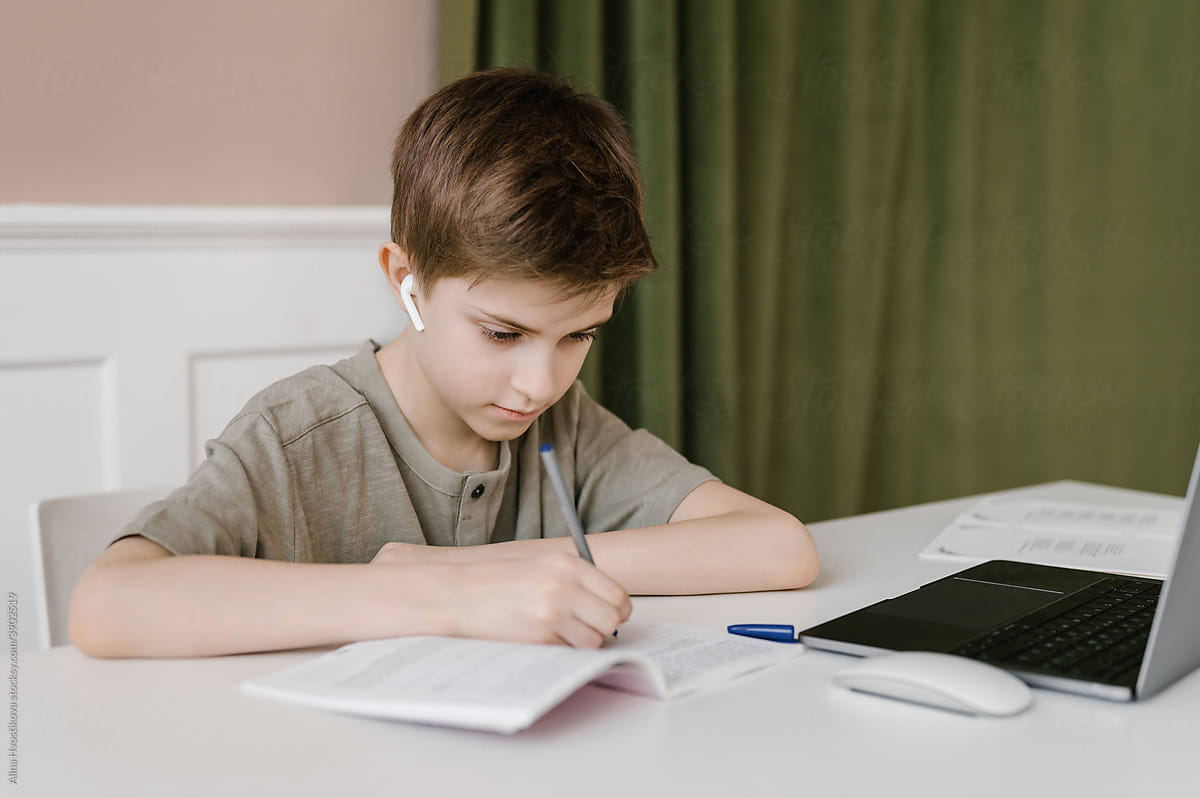 Focused boy doing homework and writing in notebook