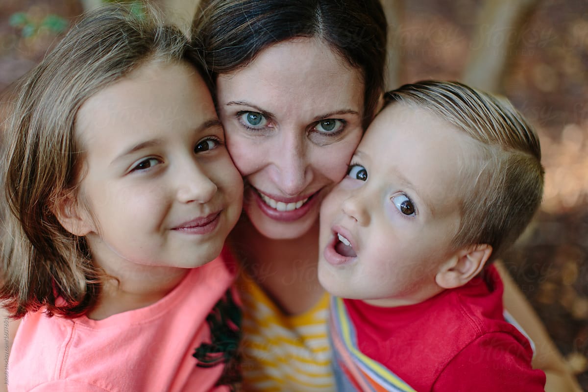 Close Up Of A Mother With Her Son And Daughter Sitting Cheek To Cheek 