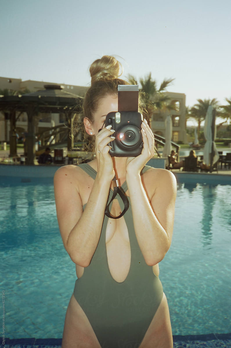Girl use instant film camera to take pictures on resort